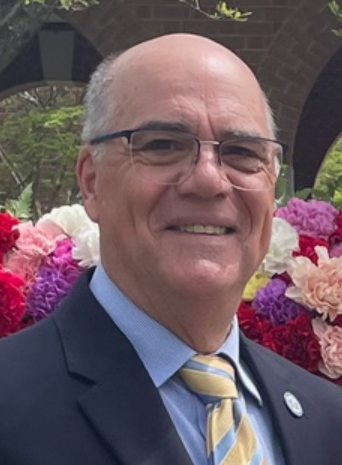 Photo of Rev. Ed Carll against a backdrop of spring flowers.